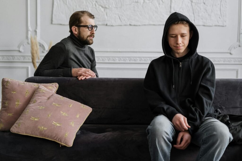 Finding the right therapist for teenagers – a teenage boy sits with folded hands while a therapist attentively looks at him during a counseling session.